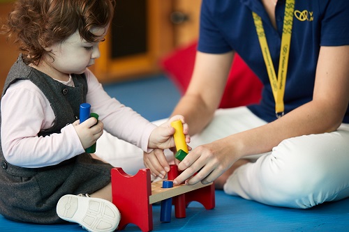 A young female Vision Australia client interacts with toys with a Vision Australia staff member