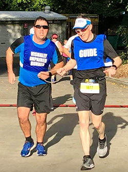 Nathan Johnston running with a guide.