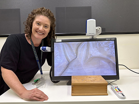 Occupational Therapist Alex Lonsdale smiling at the camera, showing a CTV device