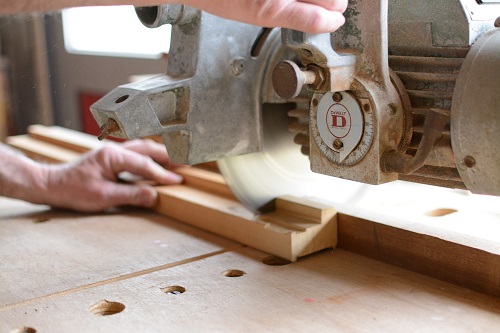 A bench top saw cuts a piece of wood