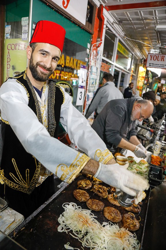 Man wearing traditional costume smiling and cooking food on a hot plate