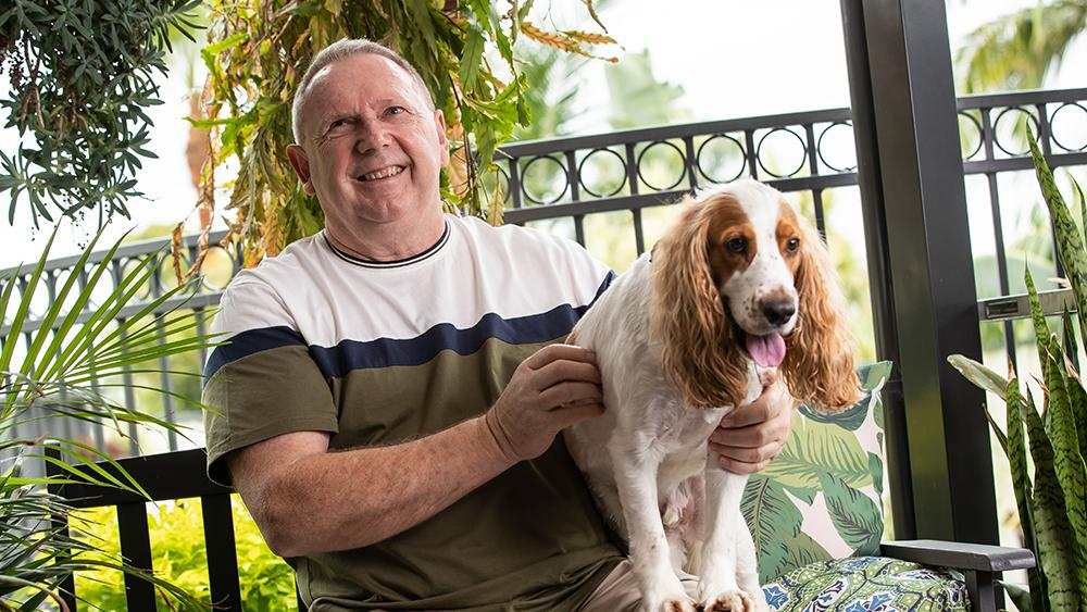 Paul smiles with his pet dog beside him